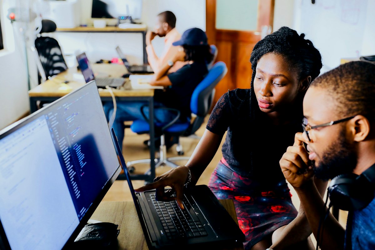 Two professionals working through a problem together at a laptop